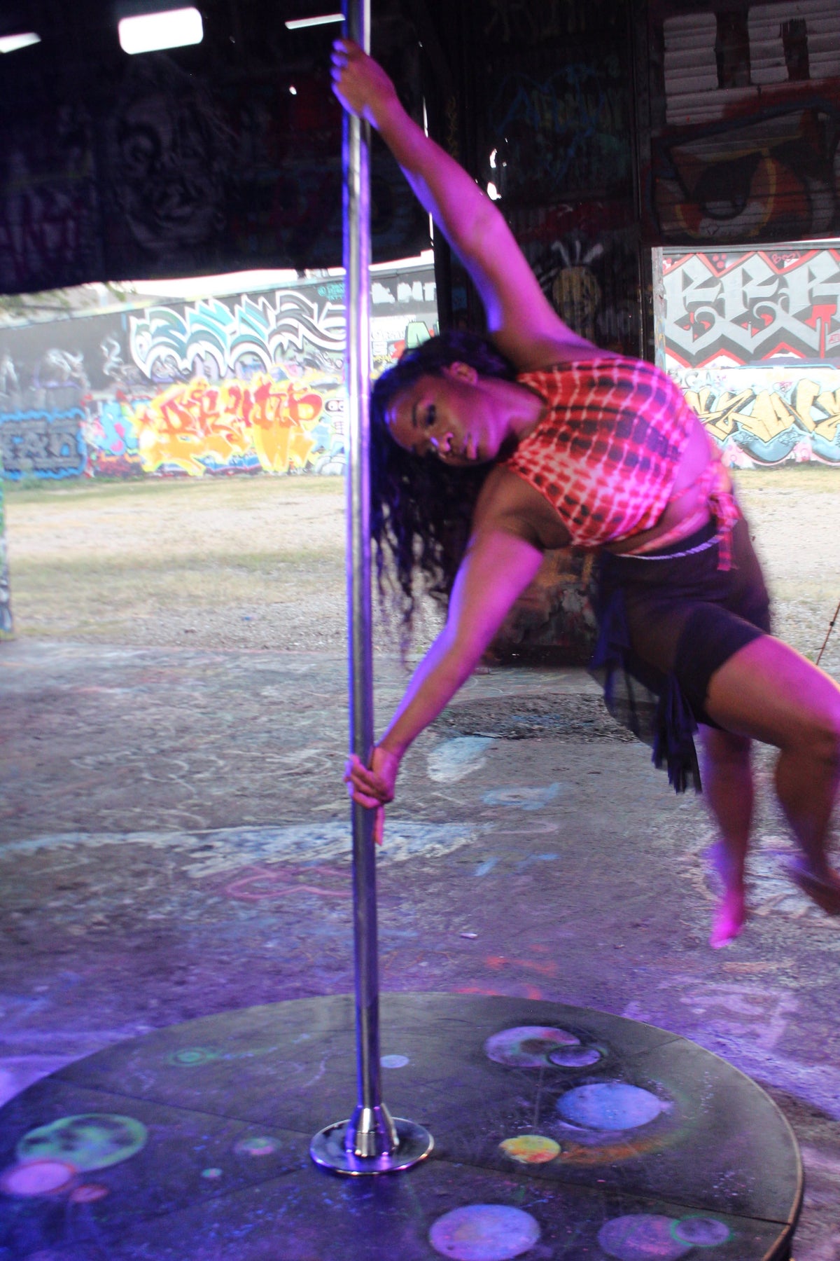 Tiffany on a stage pole under purple lights